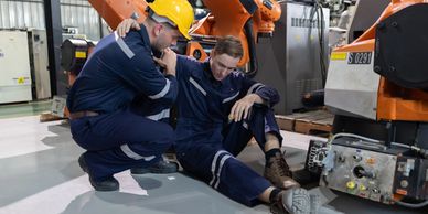 Worker comforting injured colleague in a factory.