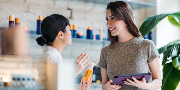 Two women discussing skincare products in a bright store.