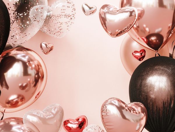 Metallic and transparent heart-shaped balloons framing a soft pink background.