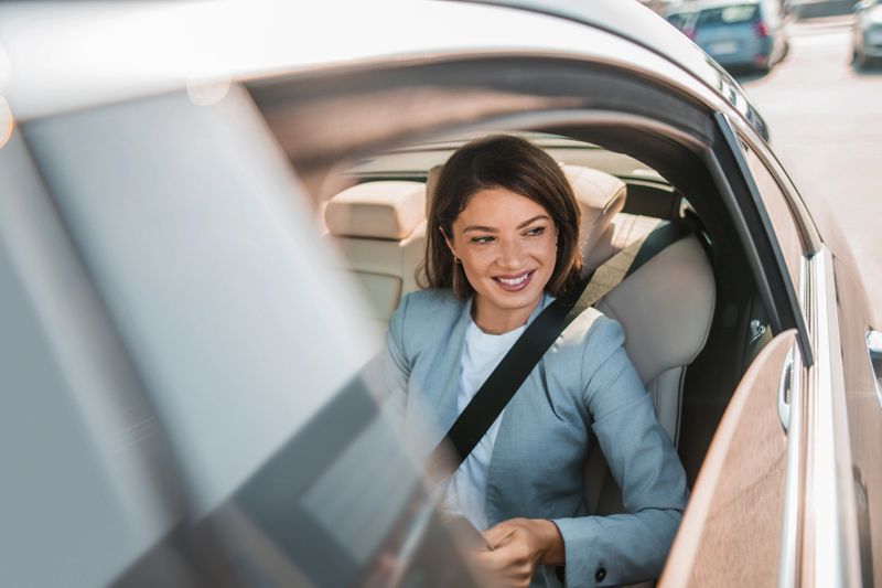Businesswoman going on a business trip on a backseat of a luxurious automobile