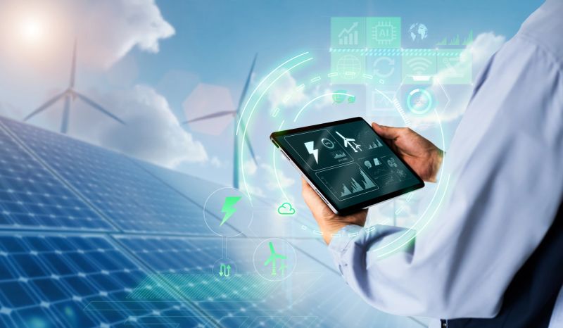 Engineer using digital tablet with wind turbine and solar panels powerplant as background