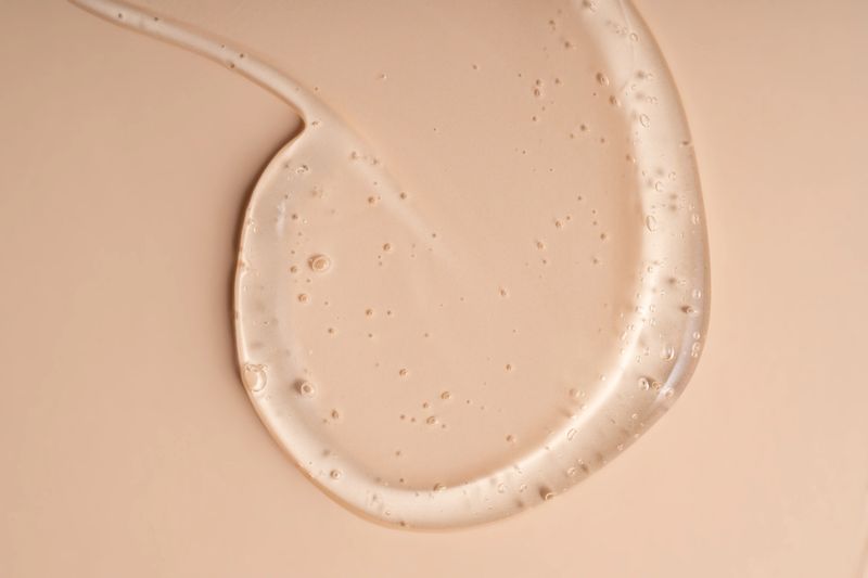 Liquid gel smear isolated on beige background. Beauty cosmetic smudge such as pure transparent aloe lotion, facial jelly serum, cleanser, shower gel or shampoo top view.