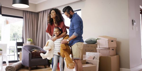 Family unpacking boxes in their new home with stuffed animals.
