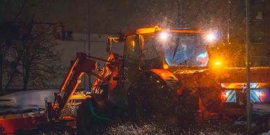 Snowplow truck clearing snow at night.