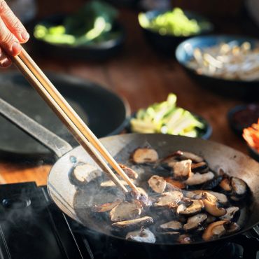 Sautéing mushrooms in a pan with chopsticks.