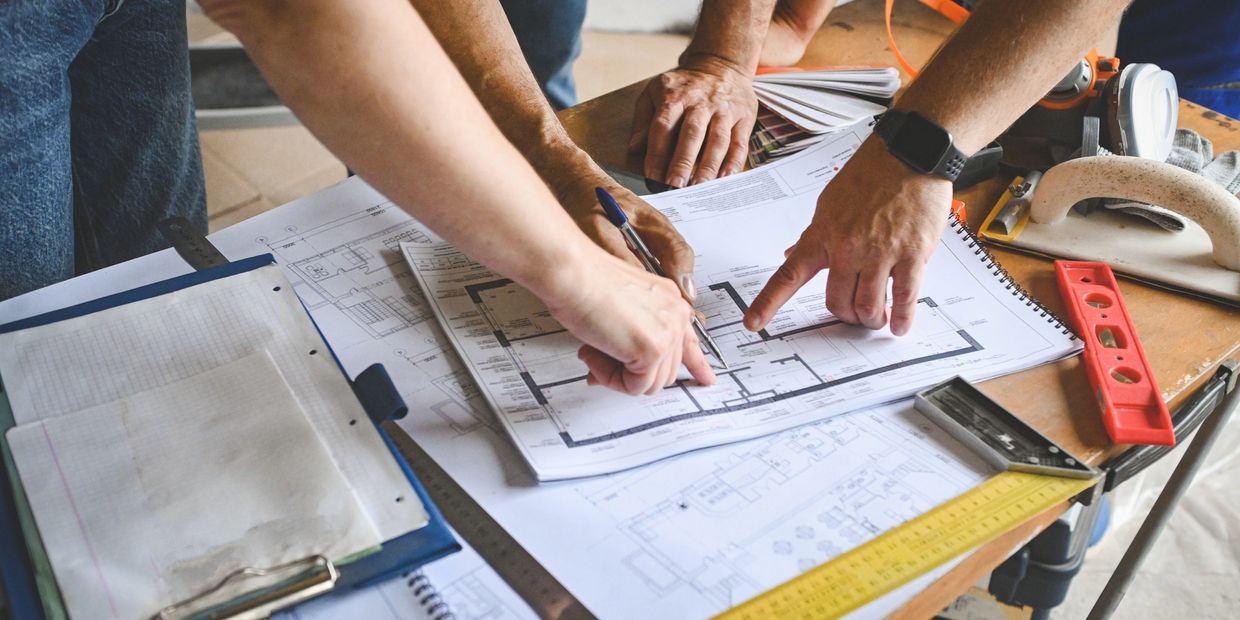 People discussing architectural plans on a table.