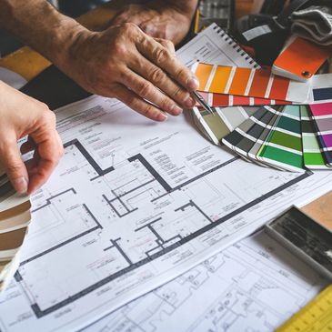 Hands selecting paint colors over architectural blueprints.