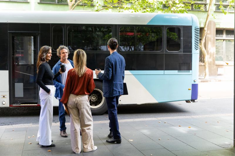 Group of colleagues wait for their bus while commuting in the city