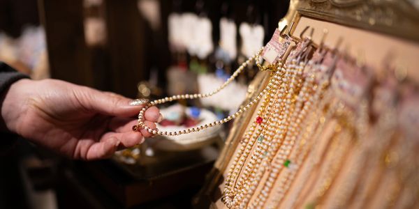 Hand holding a beaded necklace from a jewelry display.