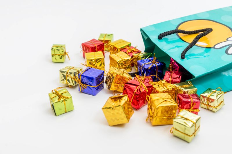 Colorful miniature gift boxes spilling from a festive green bag. Perfect for gift-giving, holidays and happy occasions.