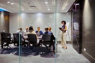 A businesswoman presenting to colleagues in a modern conference room.