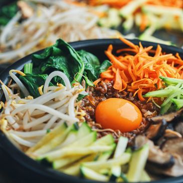 Colorful bibimbap bowl with fresh vegetables and raw egg yolk.
