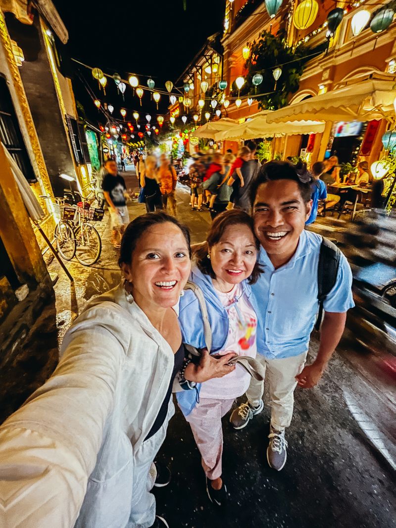 Friends posing happily on a bustling street at night, colorful lanterns illuminating the scene. Joyful group smiling under festive lights. Capturing vibrant nightlife fun.