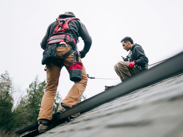 Two men working safely on a sloped roof.