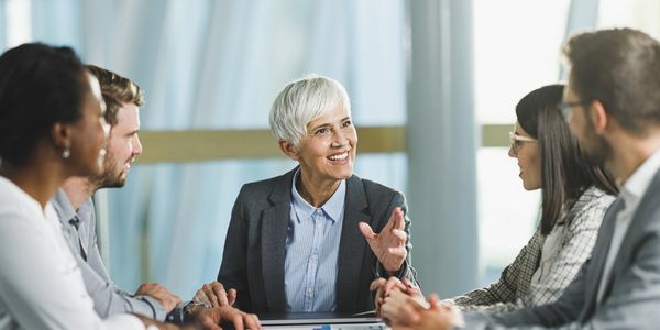 Senior businesswoman leading a meeting with engaged colleagues around a conference table.