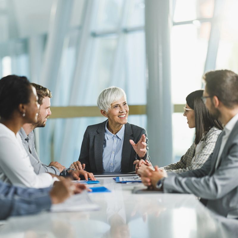 Happy senior businesswoman talking to her team on a meeting in the office.
