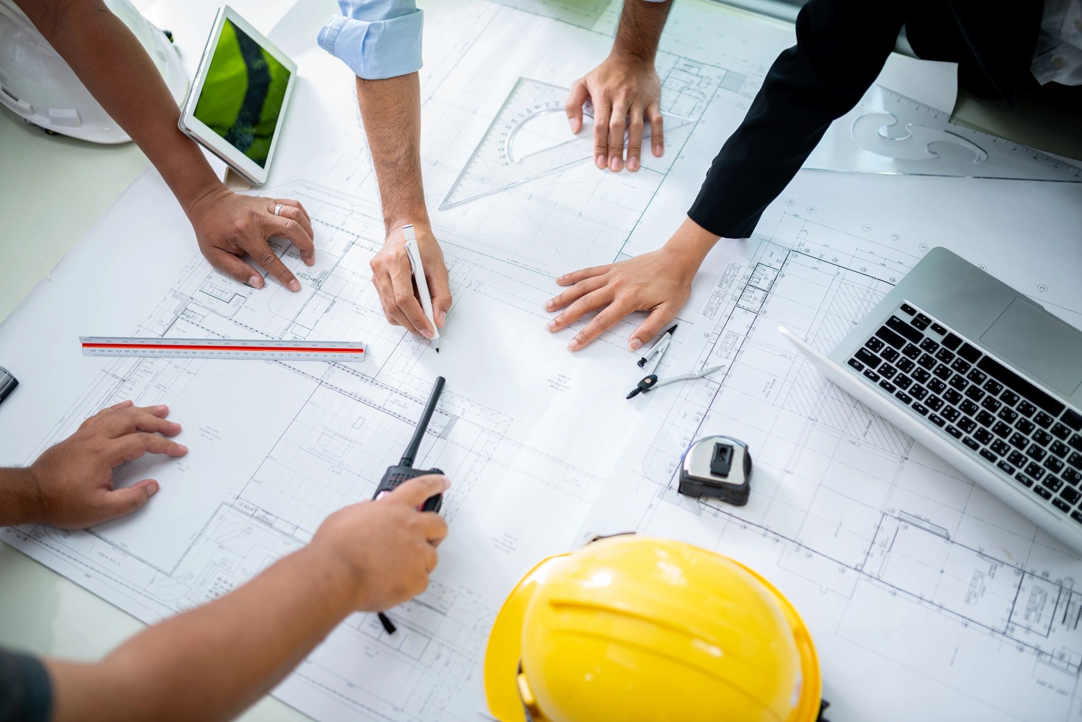 Team collaborating over architectural blueprints with tools and technology.