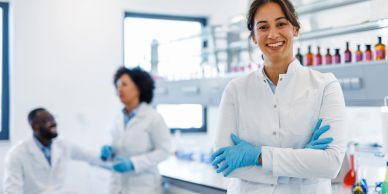 Smiling female scientist in lab coat and gloves.