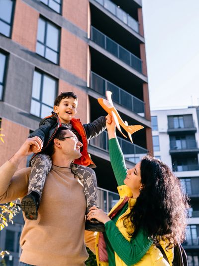 Family enjoying a sunny day with their child playing with a toy airplane.