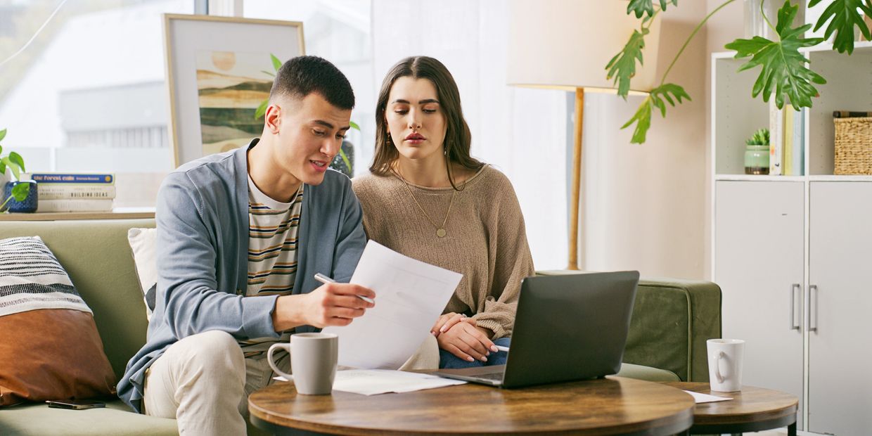 A young couple reviews documents together in a cozy living room.