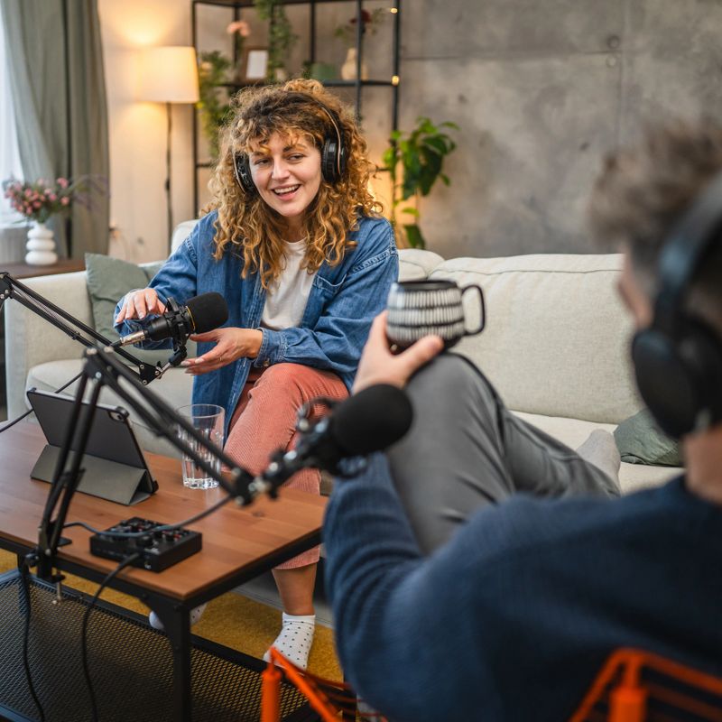 focus on female guests with headphones answer on questions to male presenter and record fresh episode at home studio