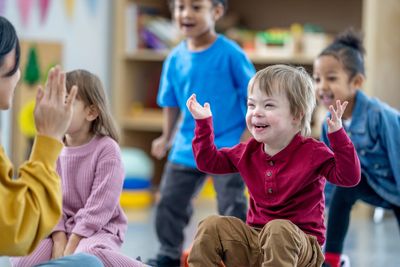 Happy children playing and interacting in a classroom with a teacher.