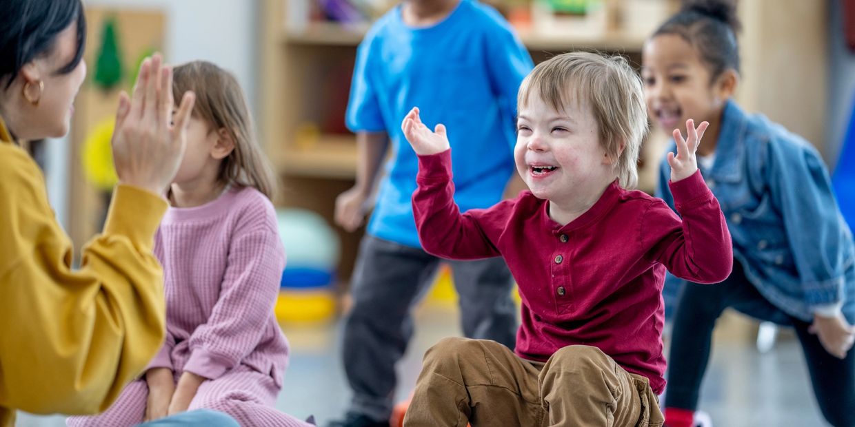 Happy children playing and interacting in a classroom with a teacher.