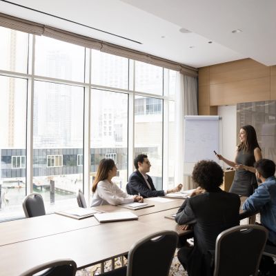 Business meeting with a presenter and four attendees in a modern office.