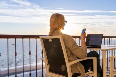 professional woman working on her laptop, sitting near the ocean