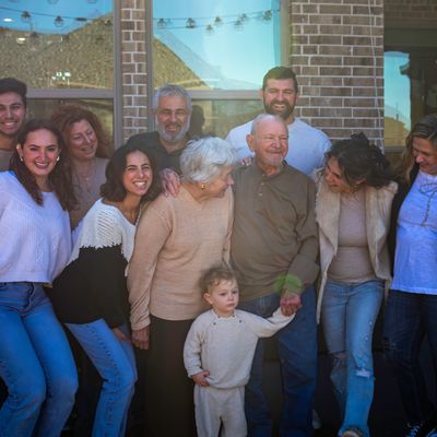 Large family group smiling and enjoying time together outside a house.