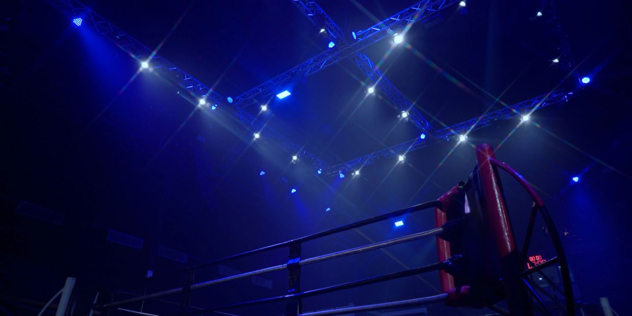 Empty boxing ring under blue spotlights.