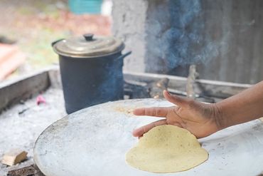 Hand cooking flatbread on a traditional stove.
