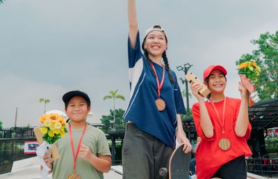 Three kids celebrating with medals and flowers.