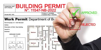 Hand marking a building permit as approved with a green check mark.