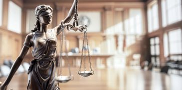 Statue of Lady Justice holding scales in a bright courtroom.