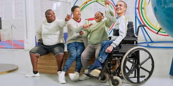 Group of happy friends, including one in a wheelchair, enjoying time together indoors.