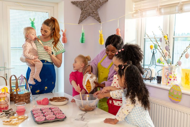 A wide shot of two families gathering in a festive kitchen, baking treats together. A woman mixes chocolate with children in aprons, while another holds a baby, surrounded by Easter decorations. Joyful and heartwarming holiday moments.

Videos are available similar to this scenario.