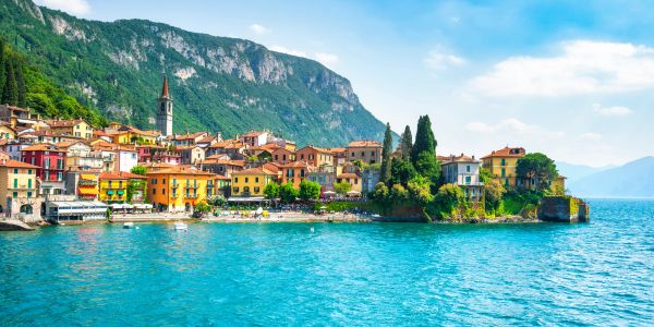 Colorful lakeside village with mountains in the background.