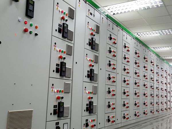 Long row of industrial control panels with buttons and displays.