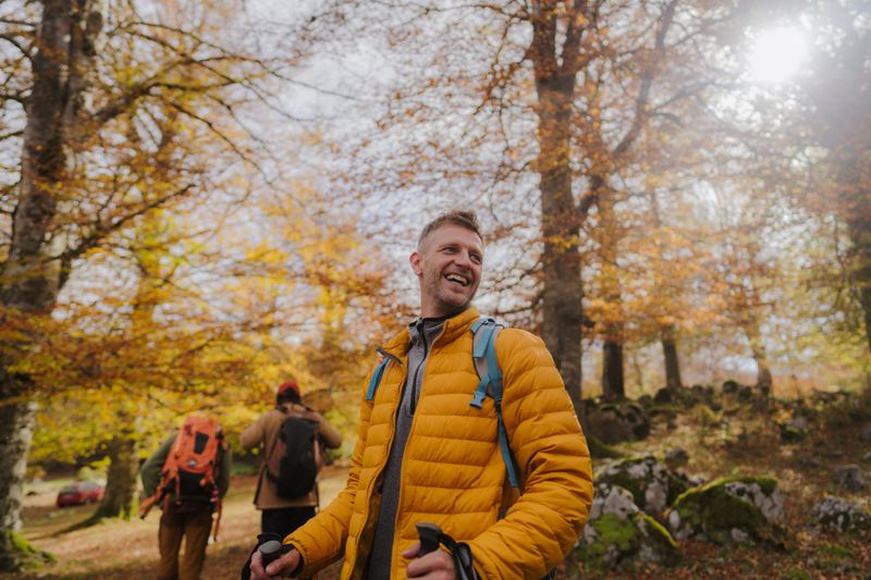 Photo of a diverse group of people, having a walk with backpacks through beautiful nature on a beautiful and sunny autumn day