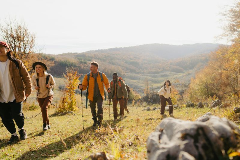 Photo of a diverse group of people, having a walk with backpacks through beautiful nature on a beautiful and sunny autumn day