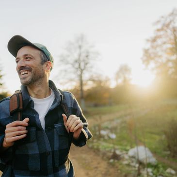 Smiling man with backpack enjoying a sunny outdoor walk.