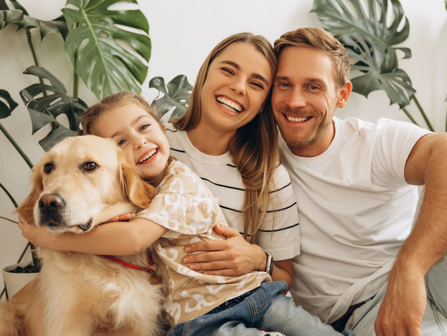 A happy family with their dog smiling at the camera indoors.