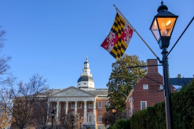 Maryland State House with flag and lamp post at dusk.