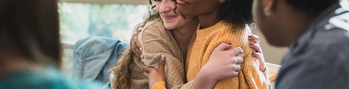 Two women sharing a warm embrace indoors.