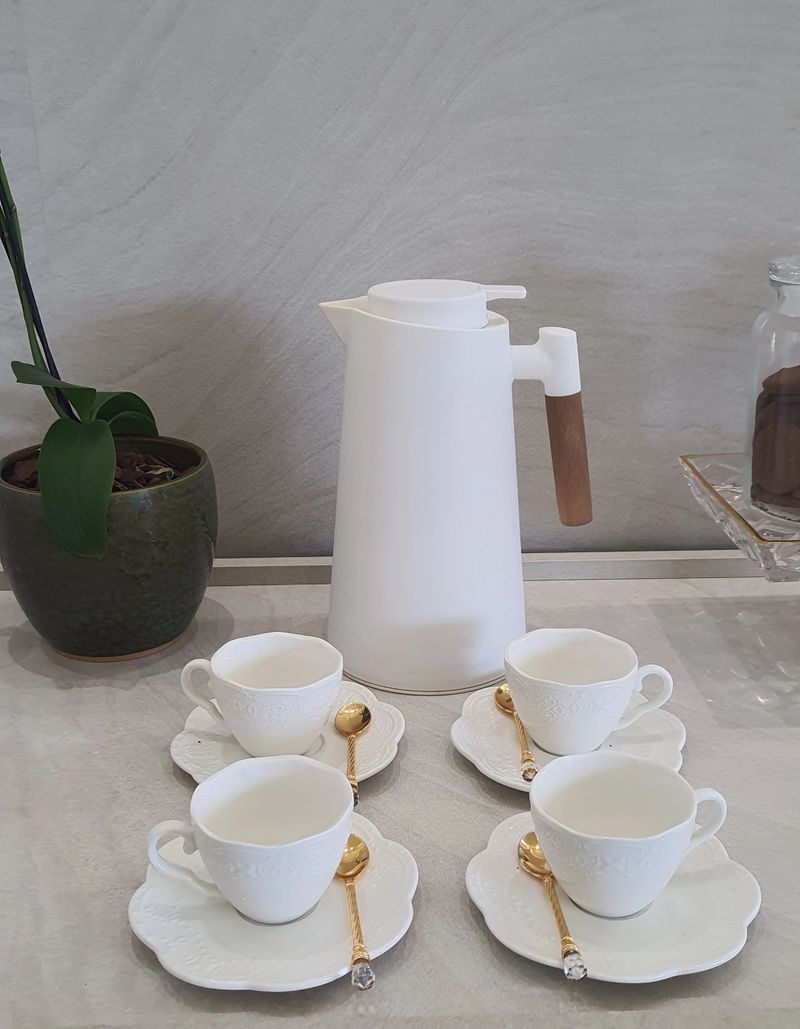 Cups with golden spoons and thermos for serving coffee