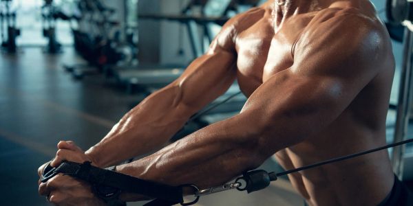 Muscular man training with cable machine.