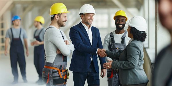 Construction workers and a businesswoman shaking hands.