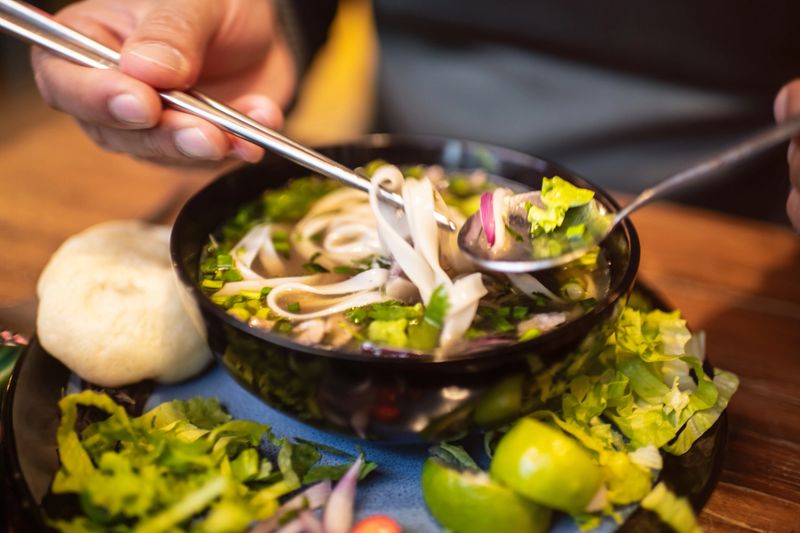 Close-up of a man eating Vietnamese dish Pho Bo soup in a cafe