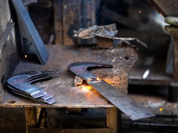 Metal pieces being heated on a workshop table for forging.